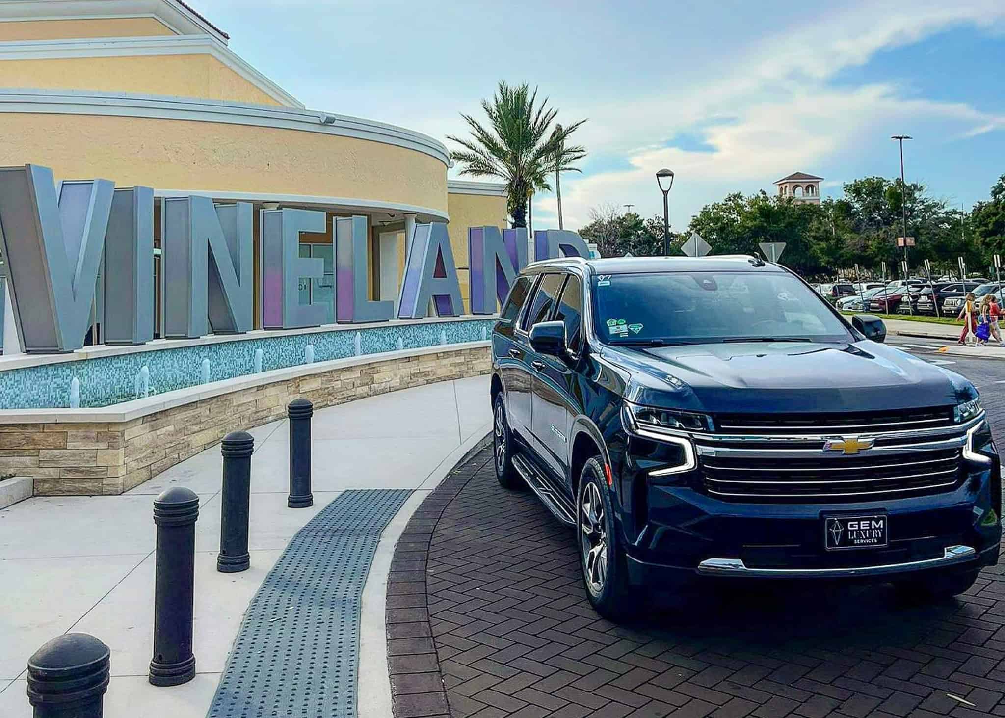 Luxury SUV by Gem Luxury Services at Vineland Outlets Orlando Gem Luxury Services SUV parked in front of Vineland Premium Outlets in Orlando, Florida, ready for private shopping transfers.